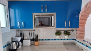 Una cocina con armarios azules, horno empotrado, fregadero y tostadora.
