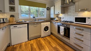 Une cuisine compacte équipée d’un lave-vaisselle, d’un lave-linge, d’un four à micro-ondes et d’une cuisinière à gaz.