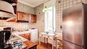 A kitchen with wooden cabinets, a stainless steel refrigerator, a coffee maker, and a window with a view.