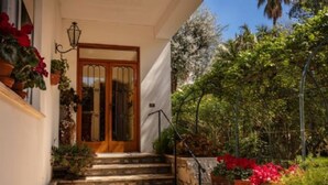 A house with a wooden door, steps leading to a porch, and potted plants.