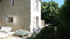 A stone building with a bench and a pathway leading to a door.