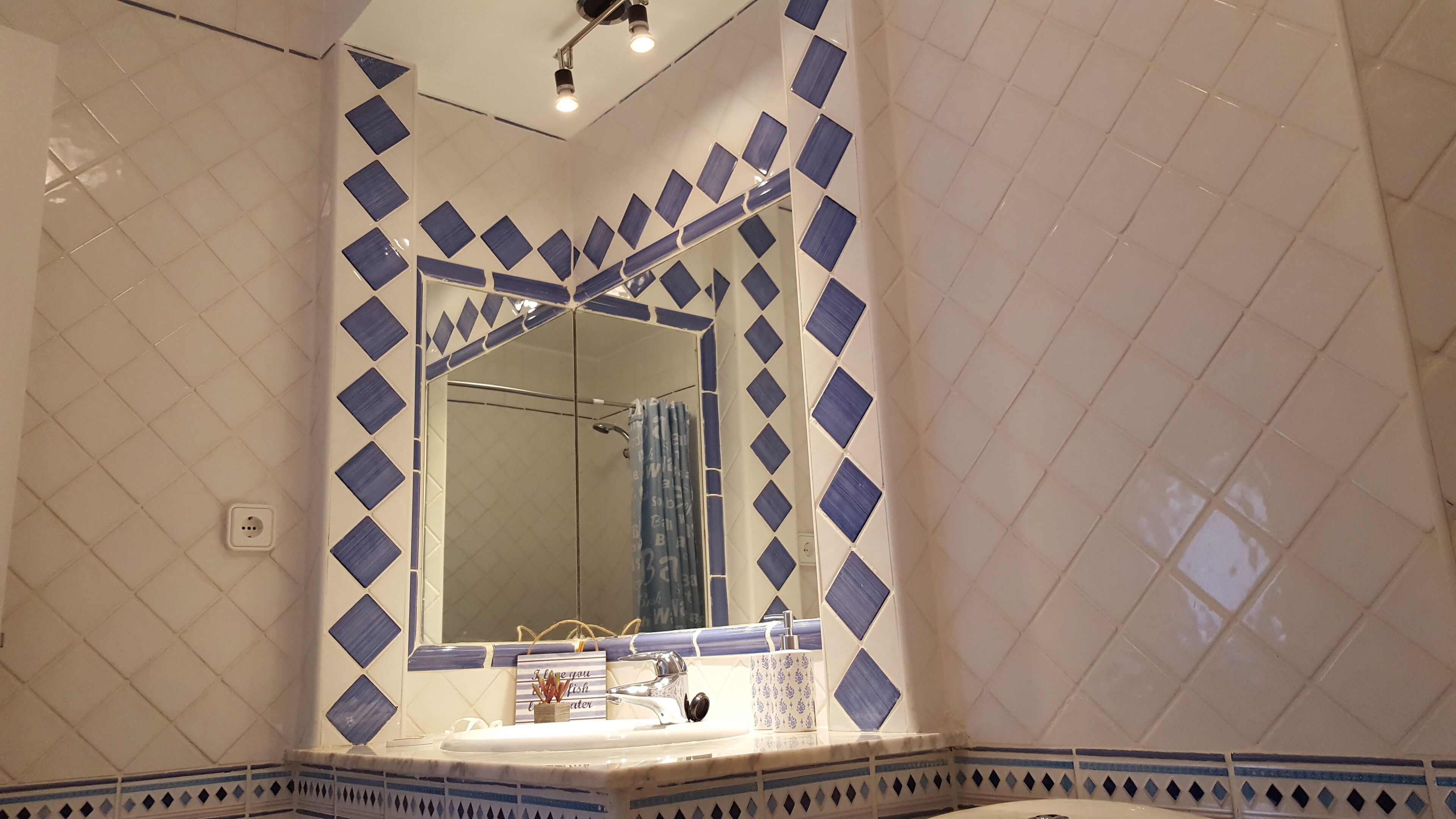 A bathroom with a large mirror, a sink, and a shower area.