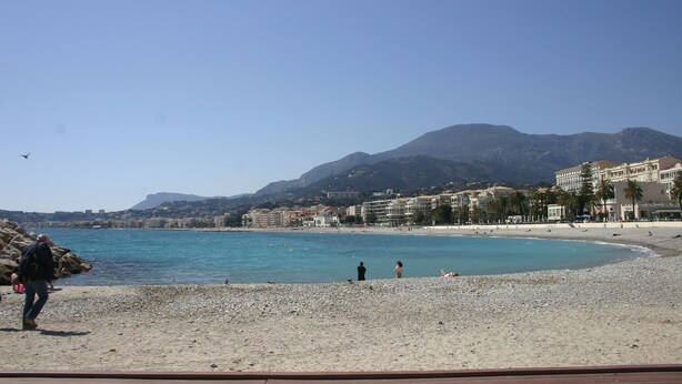 A beach with clear blue water, a rocky shoreline, and buildings in the background. - Historic House With Stunning Mountain Views in the heart of the village      (Pigna)