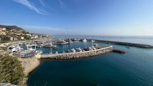 A marina with boats docked, a pier, and a rocky breakwater. - Historic House With Stunning Mountain Views in the heart of the village      (Pigna)