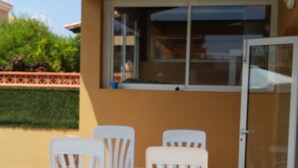 Un patio con una mesa, cuatro sillas, un ventanal corredero y una ventana.