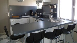 A compact kitchen with a sink, coffee maker, toaster, and a clock on the wall. - duplex apartment 50m from the Arcachon Basin (Lège-Cap-Ferret)