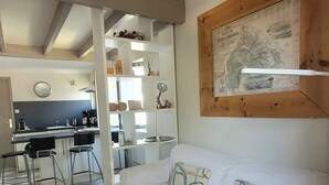 A cozy room with a white sofa, a woven basket, and a kitchen area in the background. - duplex apartment 50m from the Arcachon Basin (Lège-Cap-Ferret)
