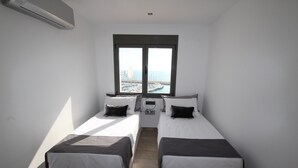 Une chambre avec deux lits, une fenêtre donnant sur une marina et un appareil de climatisation.