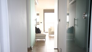 Un couloir mène à un espace de vie comprenant un canapé et un fauteuil.