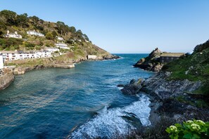 A coastal town with buildings on a hillside, a rocky shoreline, and a clear view of the sea. - Stunning house right by the sea, spectacular far reaching sea views in Polperro (Polperro, Cornwall)