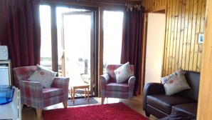 A cozy living room with plaid furniture, a red carpet, and a wooden wall.
