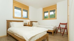 A bedroom with two single beds, wooden headboards, and a red chair. - Chalet Anna - La Tzoumaz, 4 Vallees (La Tzoumaz)