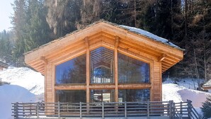 A wooden chalet with large windows, a balcony, and a staircase leading up to it. - Chalet Anna - La Tzoumaz, 4 Vallees (La Tzoumaz)