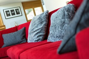 Un canapé rouge avec des coussins gris et noirs.