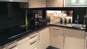 A modern kitchen with a black countertop, stainless steel appliances, and beige cabinetry. - Bahia Beach Front Apartment - Close to Marbella - Free WiFi (Estepona)