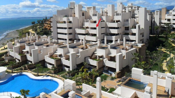 A modern hotel complex with multiple buildings, a swimming pool, and a view of the ocean. - Bahia Beach Front Apartment - Close to Marbella - Free WiFi (Estepona)
