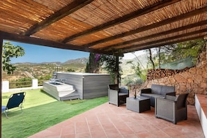 Eine Terrasse im Freien mit Grillplatz, Sitzgelegenheiten und Blick auf die Landschaft.