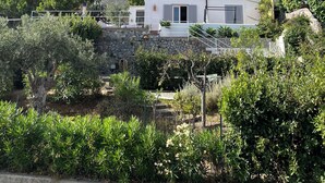 Una villa blanca con un muro de piedra y un jardín delantero.