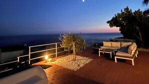 Un espacio de estar al aire libre con vistas al océano y la luna en el cielo.