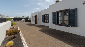 Un patio con paredes blancas, contraventanas azules y un camino empedrado.