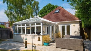 A conservatory with a glass roof, a white exterior, and a red-tiled roof. - New Forest cottage, sleeps up to 10. Looks directly on to the Forest  (Brockenhurst)