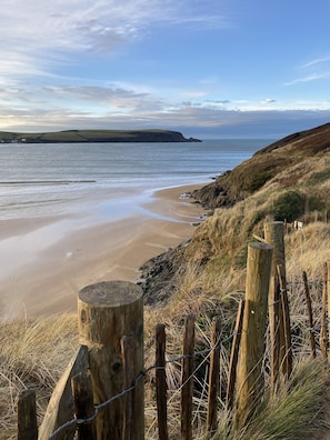 A beach with a wooden fence and a clear view of the sea. - 4-Star Family Home in Rock: private garden, walk to beach & pet friendly (Wadebridge)