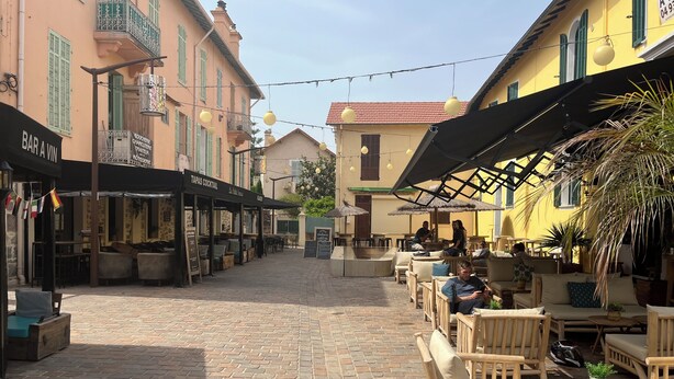 Una calle empedrada con mesas al aire libre, un bar y un restaurante.