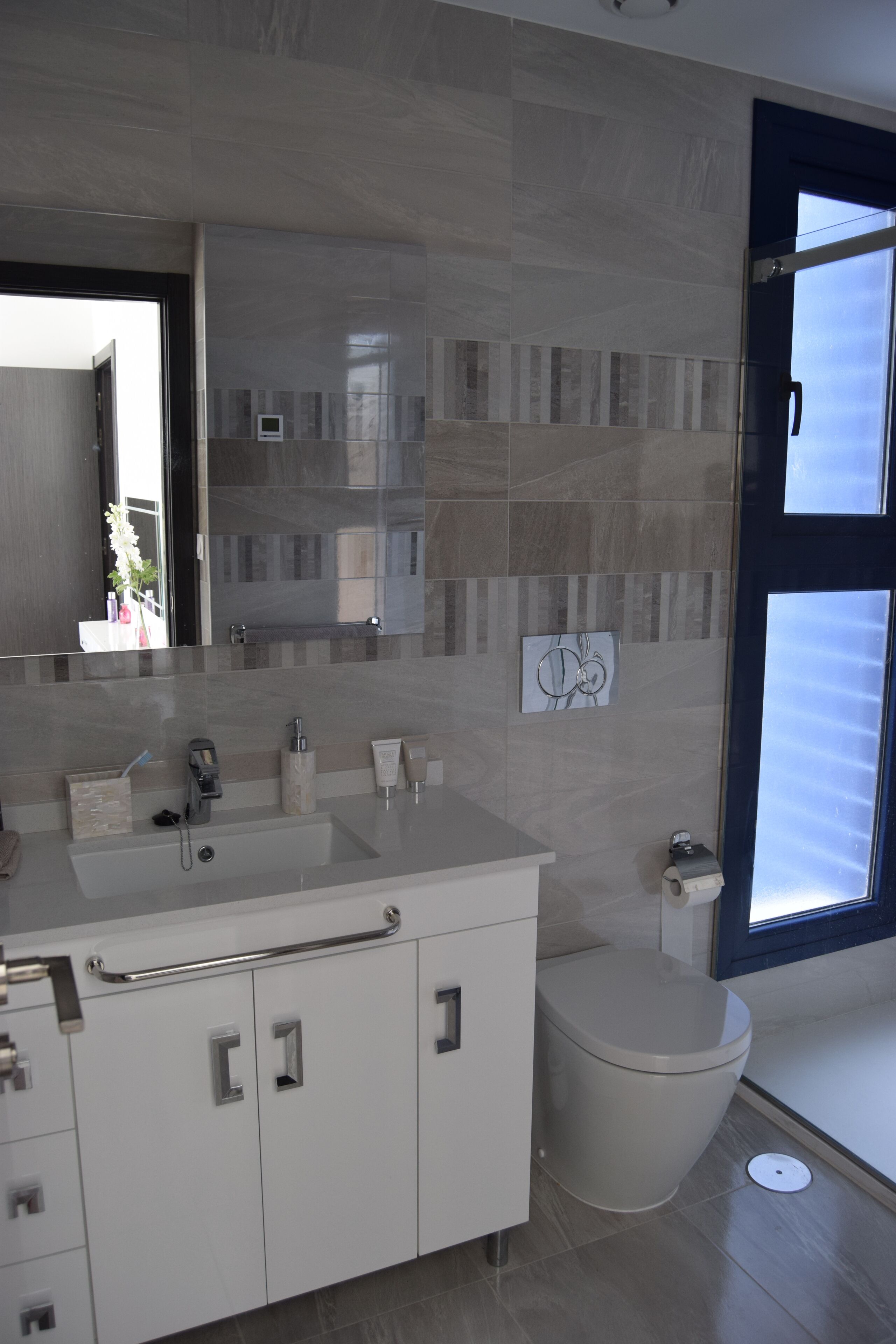 Une salle de bain moderne avec un grand miroir, un lavabo et des toilettes.