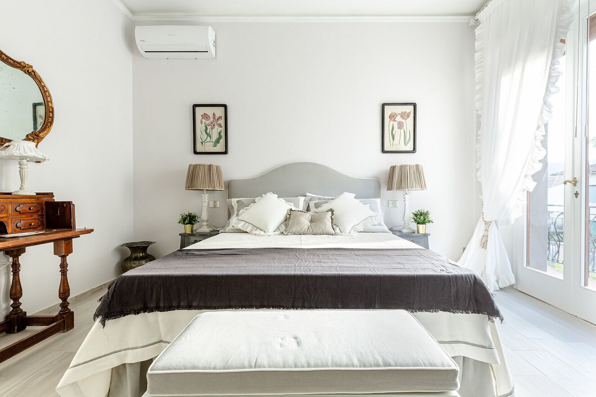 A bedroom with a bed, bedside tables, a mirror, and two wall-mounted pictures.