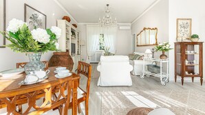 Un salón bien iluminado con comedor, muebles blancos y elementos decorativos.