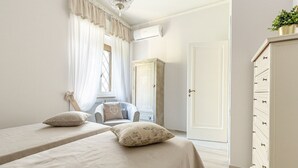 Un dormitorio con dos camas, un armario, una cómoda y una ventana con cortinas.