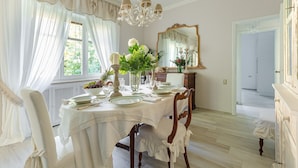 Comedor con mesa lista para cuatro personas, candelabro, espejo y vistas al exterior.