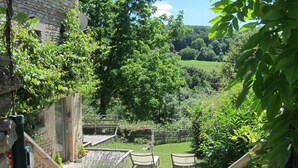 A stone building with a wooden staircase leading to a garden area with benches and a gravel path. - Picturesque. A modern barn conversion, sleeps 5. Stunning views. (Frôlois)