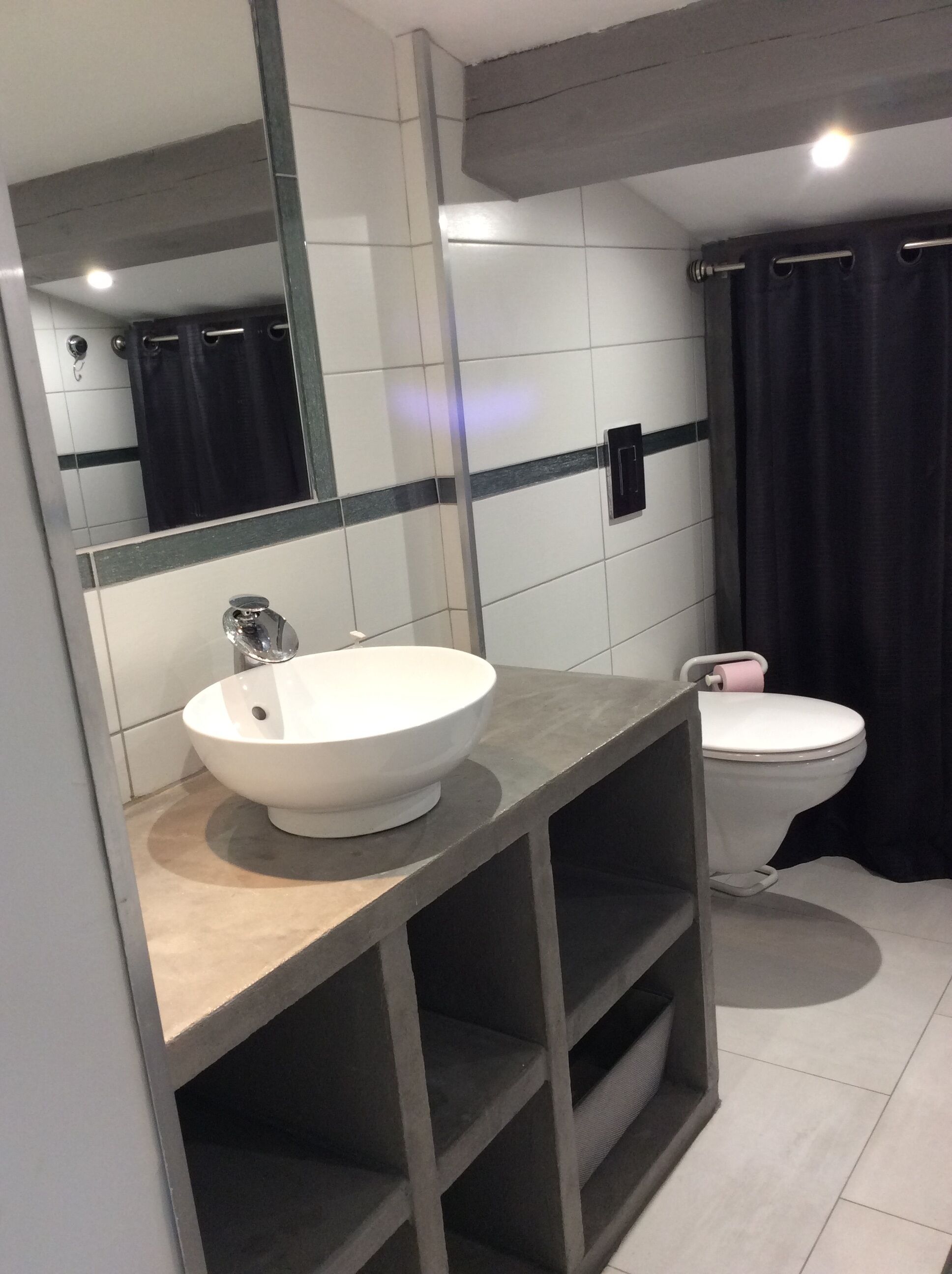 Et moderne badeværelse med en hvid vask, toilet og spejl.