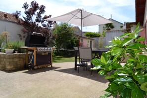 An outdoor patio area with a barbecue grill, a table, chairs, and an umbrella. - House with garden, Center La Rochelle (Rental) (La Rochelle)