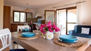 Una mesa de comedor dispuesta con platos azules, un jarrón de flores rosas y copas de vino.