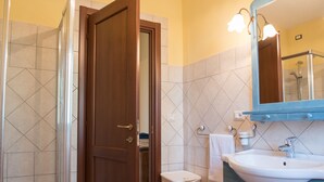 Un baño con puerta de madera, un lavabo blanco y un espejo con luces.