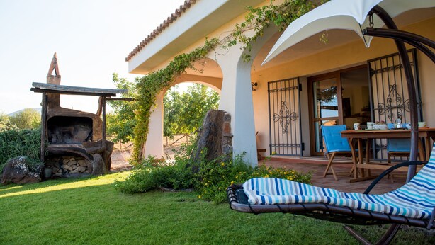 Un patio con una parrilla, una silla de descanso y una mesa con sillas.