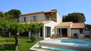 Une maison à deux étages avec une piscine, un patio couvert et un jardin.