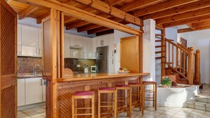 Una cocina con taburetes de madera, suelo de baldosas y una escalera.