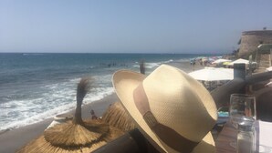 Vista de la playa con un sombrero de paja, un salero y un vaso sobre una mesa.