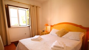 A neatly made bed with a white bedspread and two pillows, a bedside table with a lamp, and a window with curtains. - Fantastic Villa With Private Pool In Vilamoura  (Vilamoura)