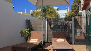 A patio with two lounge chairs and a table, a bamboo fence, and a view of buildings in the background. - Fantastic Villa With Private Pool In Vilamoura  (Vilamoura)