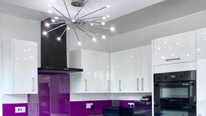 A modern kitchen with white cabinets, a black oven, and a central island. - Caithness Holiday Home (Pontypool)