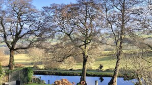 A park with a pond, trees, a bench, and a bicycle path. - Caithness Holiday Home (Pontypool)
