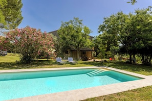 A swimming pool with a stone deck, surrounded by a grassy yard and trees. - Spacious ground floor apartment & Private Pool & large garden. wifi. Sleeps 8. (Cingoli)