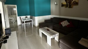 A modern living room with a grey sofa, a white coffee table, and a teal accent wall.
