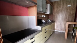 A modern kitchen with a black stovetop, yellow cabinets, and a wooden accent wall.