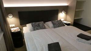 A hotel room with two beds, zebra-patterned pillows, a black towel, and a wall sign reading "Good Night Welterusten". - High Standard Renovated Apartment for up to 8 persons, in the Centre (Zermatt)