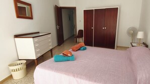 A bedroom with a bed, a dresser, a wardrobe, a chair, a fan, and a lamp. - Apartment with Sea View (Flat 5) (Triq L-Gherien, Mellieha)
